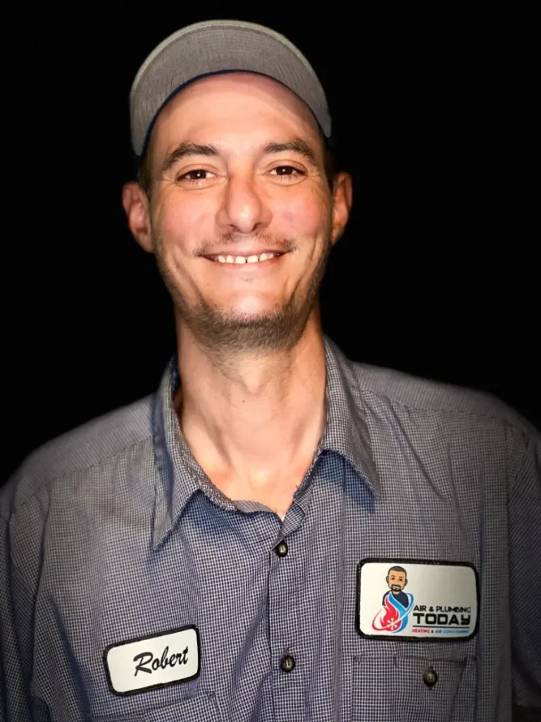 A man in a checked shirt and cap, smiling, wearing a name tag that says "Robert" and an "AR Plumbing TODAY" patch—meet the friendly face behind our work on the About Us page.