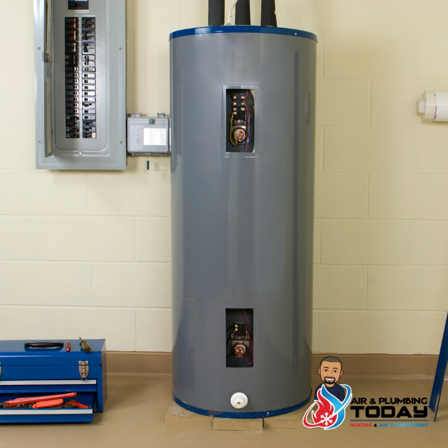 A gray electric water heater stands near a breaker panel on a beige floor, with a blue toolbox nearby and the Air & Plumbing Today logo in the bottom right corner.