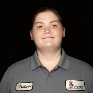 Person with short hair wearing a gray collared shirt with a name tag reading “Irelynn” and a company logo, standing against a plain black background—perfect for your About Us page.